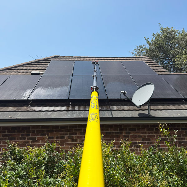 a long reach yellow xero window cleaning pole extending onto a roof to clean solar panels