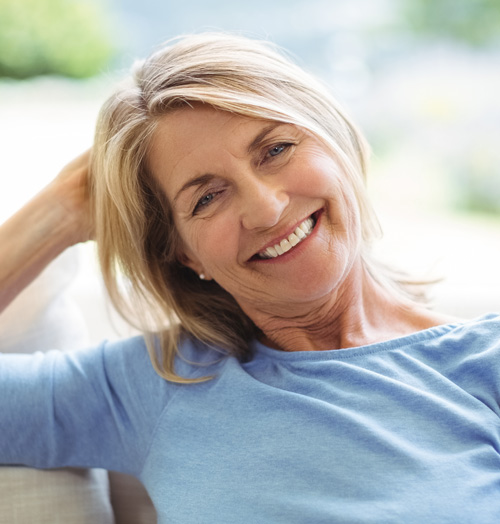 smiling lady in her mid 40s sitting on a sofa